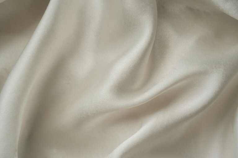 Close-up of smooth white silk fabric with soft folds and gentle draping.